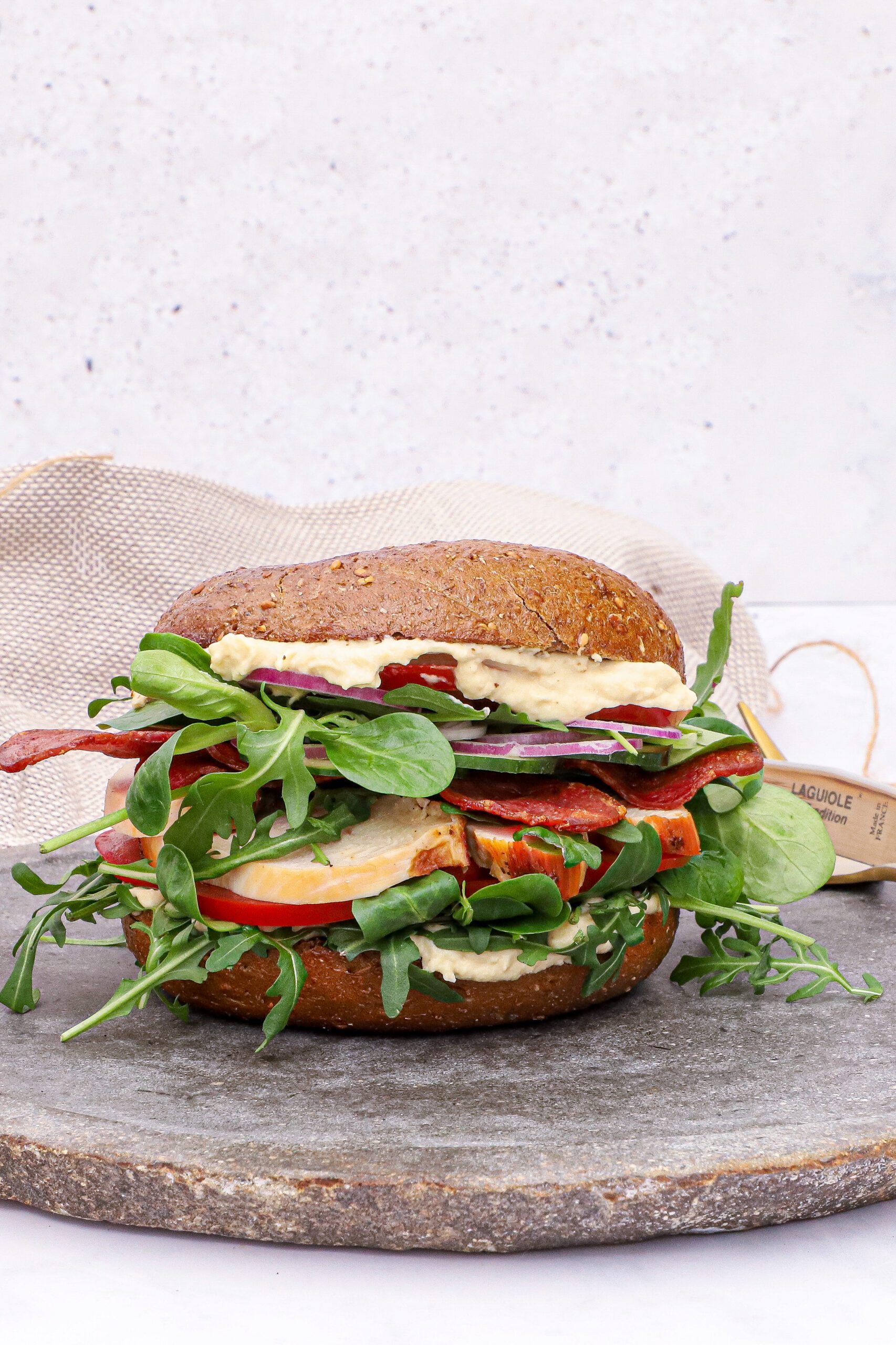 Bagel med kylling, kalkun bacon og hummus - Opskrift på sandwich