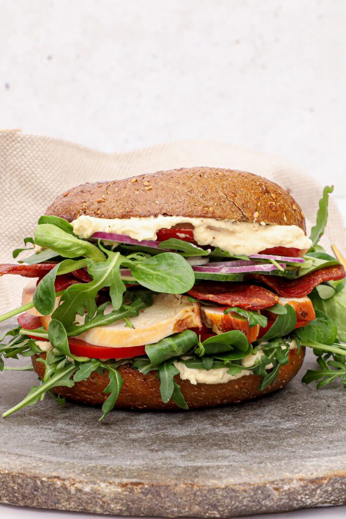 Bagel med kylling, kalkun bacon og hummus - Opskrift på sandwich